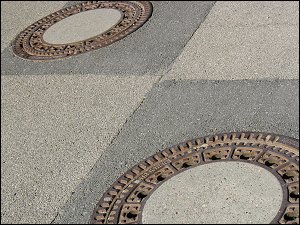 Schachtdeckel in ausgebesserter Straßendecke Schachtdeckel in ausgebesserter Straßendecke