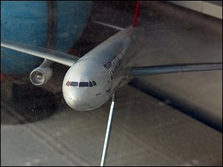 Modellflugzeug mit fehlendem Triebwerk in einem Reisebüro-Schaufenster