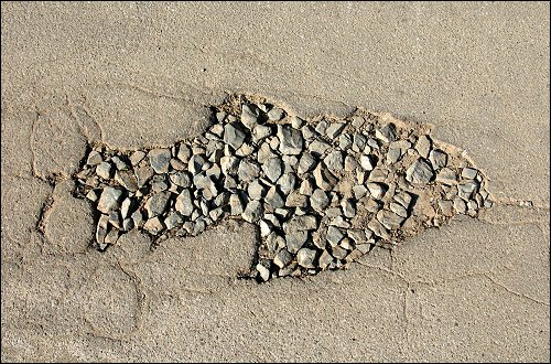 mit Schottersteinen verfülltes Schlagloch in Fischform beim Fürther Recyclinghof