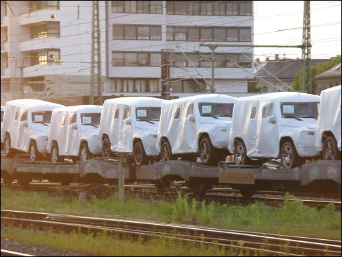 Güterzug voller Neuwagen mit weißen Schutzhauben