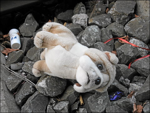 Verstoßener Plüschhund, im Bahngleisschotter liegend