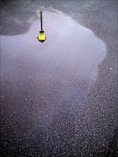 Spiegelung einer Straßenlaterne in einer Straßenpfütze